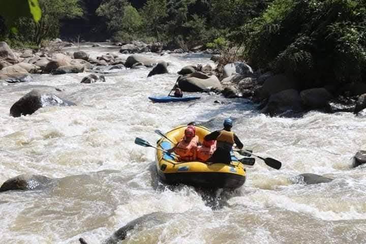 A yellow raft with a safety kayak following the Mae Taeng River between boulders